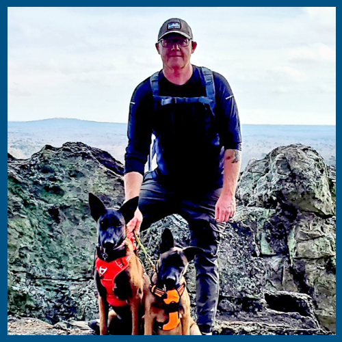 5x5 blue border Bryan Harkey on top of mountain with two Belgian Malinois dogs 