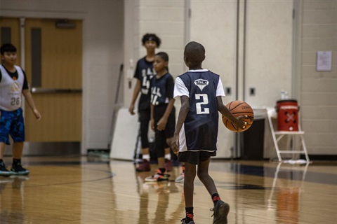 Child on a basketball court mid-dribble.