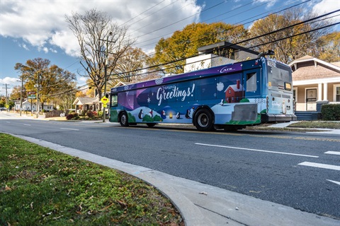 CATS 2024 Holiday bus with cartoon penguins circling a fire with the words Seasons greetings above them