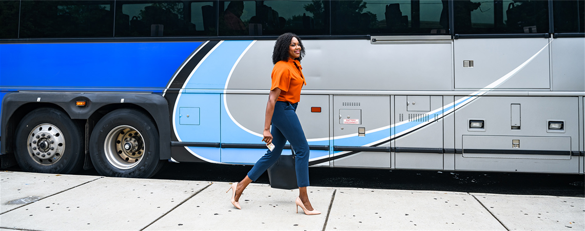Woman in an orange blouse walking alongside a CATS bus