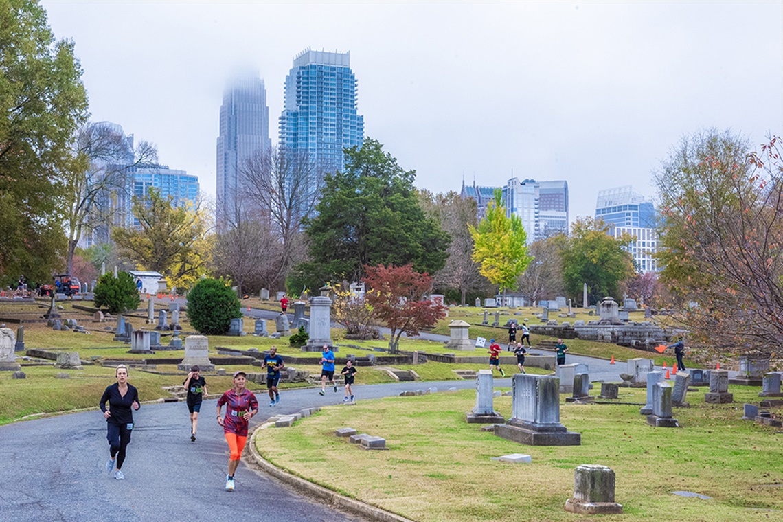 Runners going by gravesites with Charlotte skyline in the distance. Photo by Austin Caine Photography