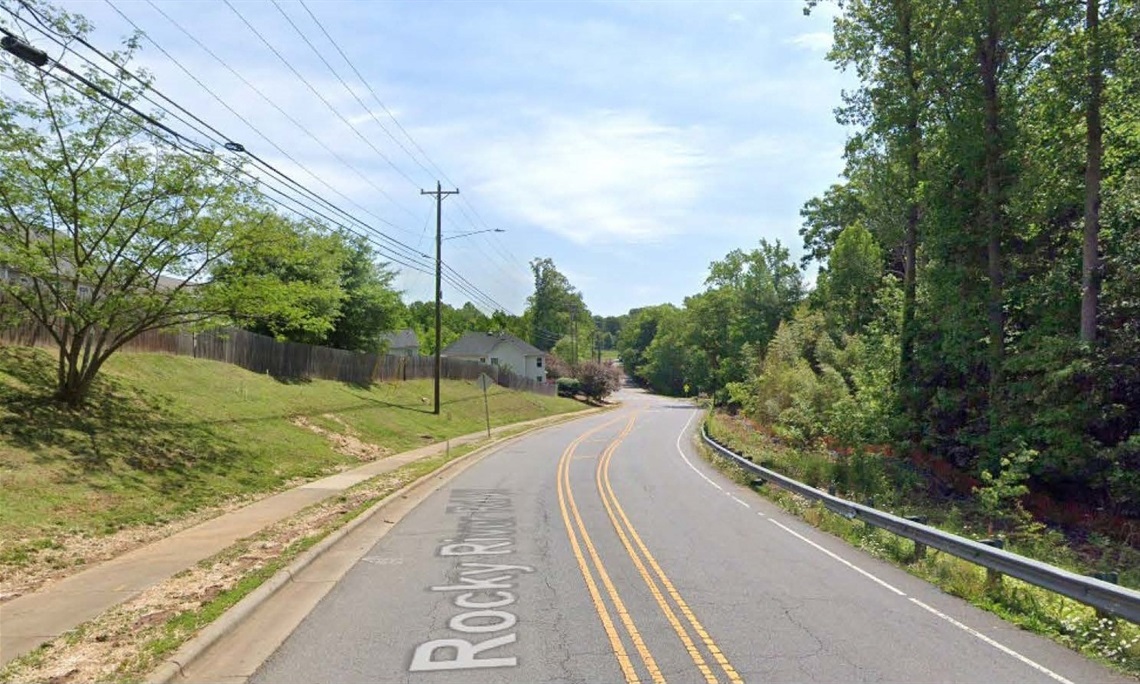 View of the roadway with a sidewalk on the left and a barrier on the right