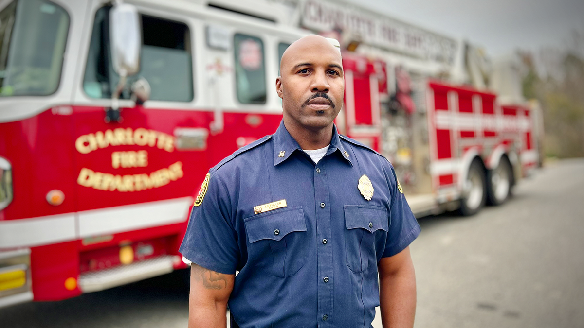 Positioned in front of a Charlotte Fire truck, Captain Fuller exemplifies courage and service. As a firefighter and mental health advocate, he has made it his mission to improve lives and strengthen his community. 