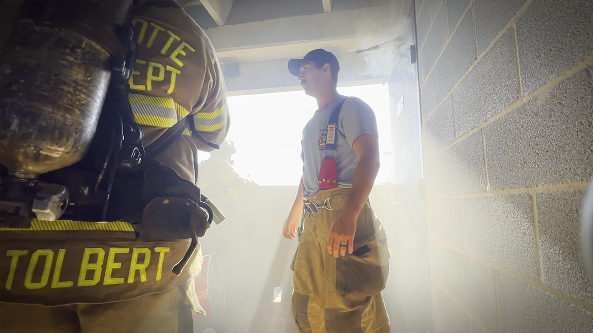 Training Captain Stephen Pettit provides guidance as recruits navigate the intensity of fire training at the Charlotte Fire Training Academy. 