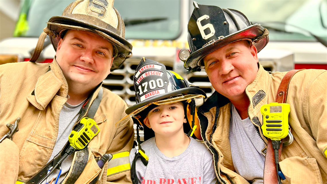 Dakota Shuford poses proudly with Charlotte Fire's Engine 6 crew members, Capt. Jason Clark and Engineer Jeffrey Field, who came to celebrate his last day of cancer treatment at Levine Cancer Institute. 