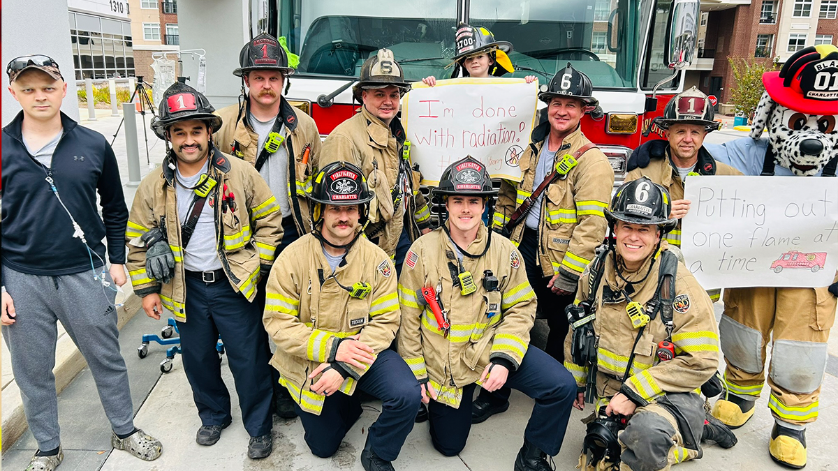 Dakota stands alongside Charlotte Firefighters from Ladder 1 and Engine 6, including Firefighter Hunter Pearson (far left), who is also bravely battling cancer, as they celebrate Dakota's final day of cancer treatment.