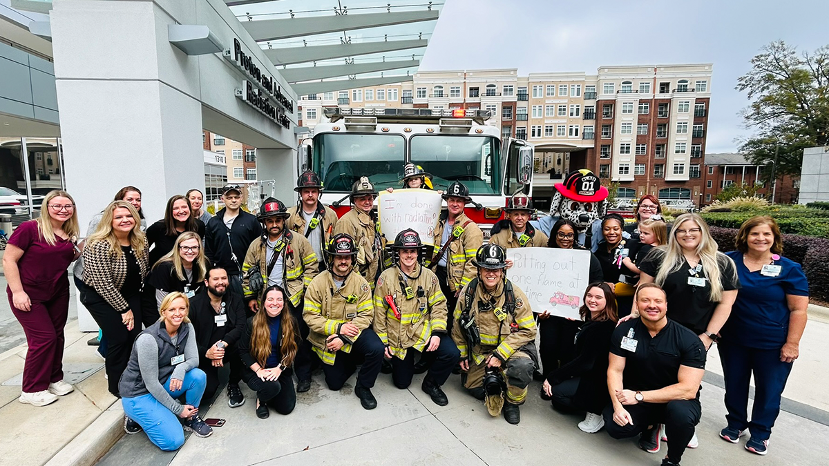 Surrounded by his family, medical team, friends, and Charlotte Firefighters, Dakota smiles in front of Engine 6, marking the end of his challenging cancer treatment journey.