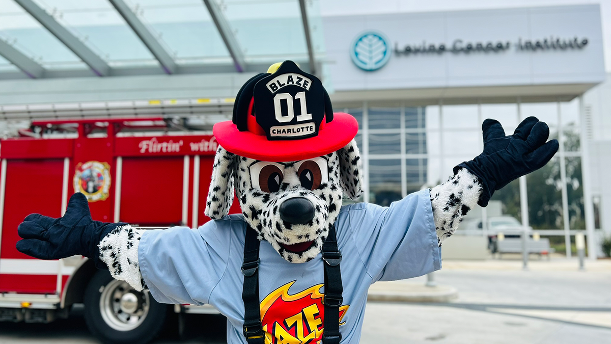 Charlotte Fire’s mascot, Blaze, strikes a celebratory pose in front of the Levine Cancer Institute, showing support for Dakota's final treatment day. 