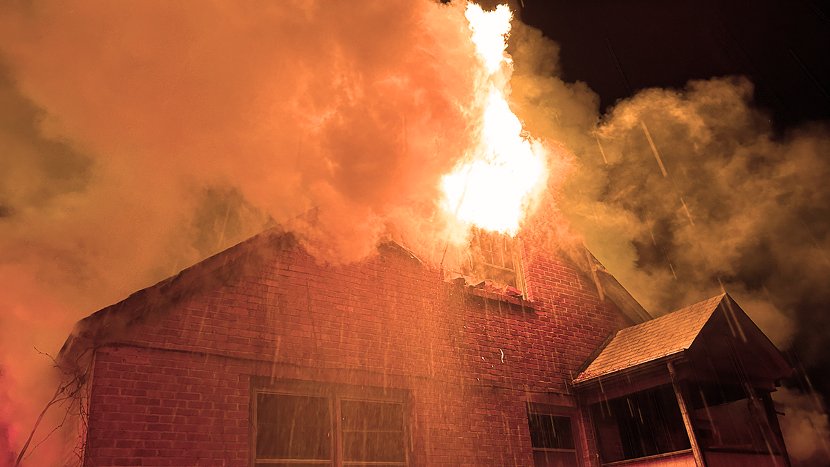 Flames erupting through the roof of the structure as firefighters work to contain the blaze.