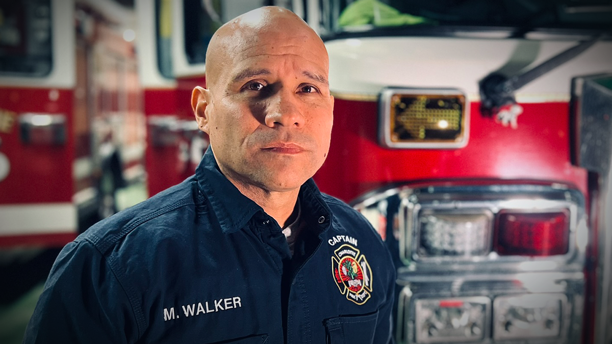 Standing in front of Ladder 16 at Charlotte Firehouse 16, Captain Matthew Walker reflects on his 18-year career and personal journey through firefighting and cancer survival. 