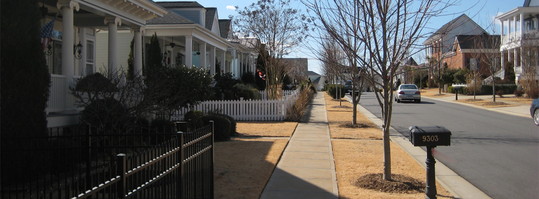 sidewalk view of neighborhood with fenced lawns