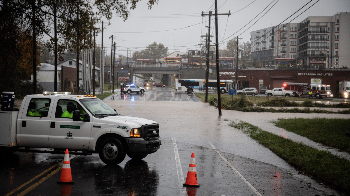 A city vehicle blocks a flooded road to prevent drivers from entering dangerous conditions.