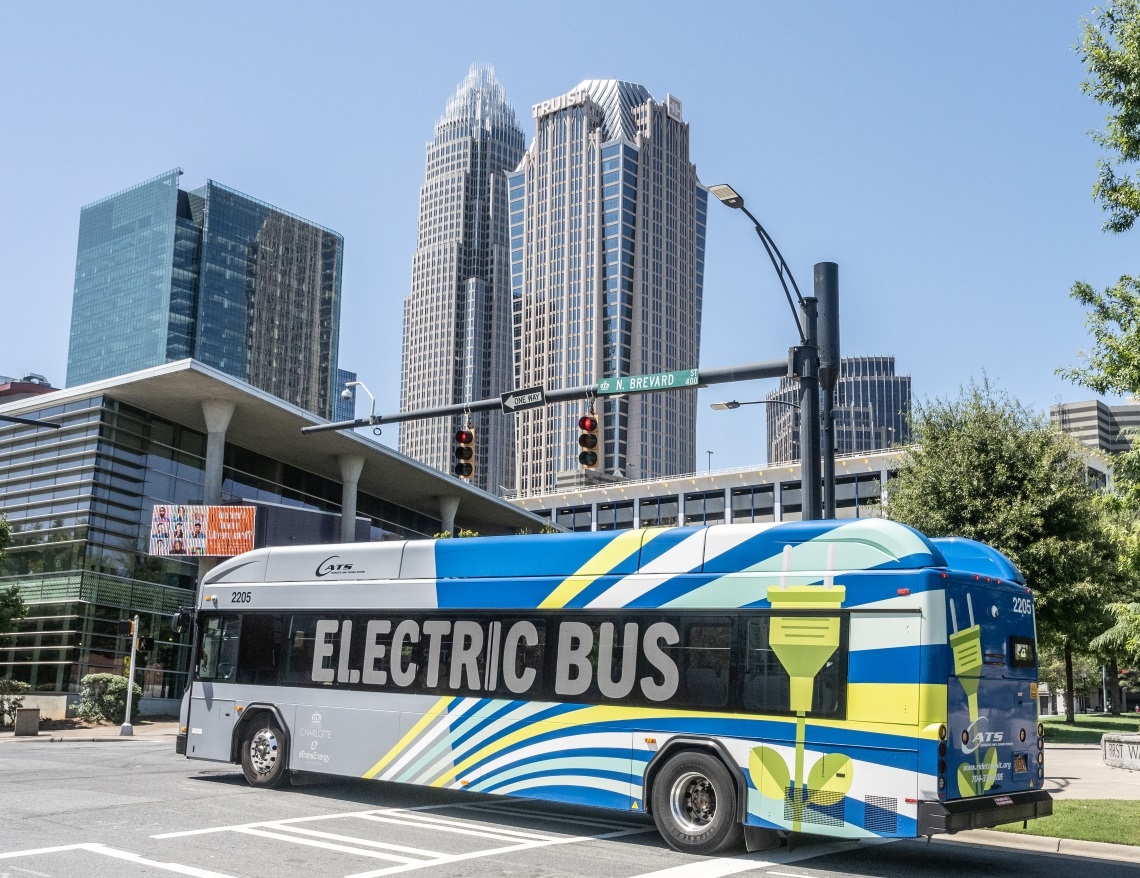 Electric CATS bus drives past the Charlotte skyline.