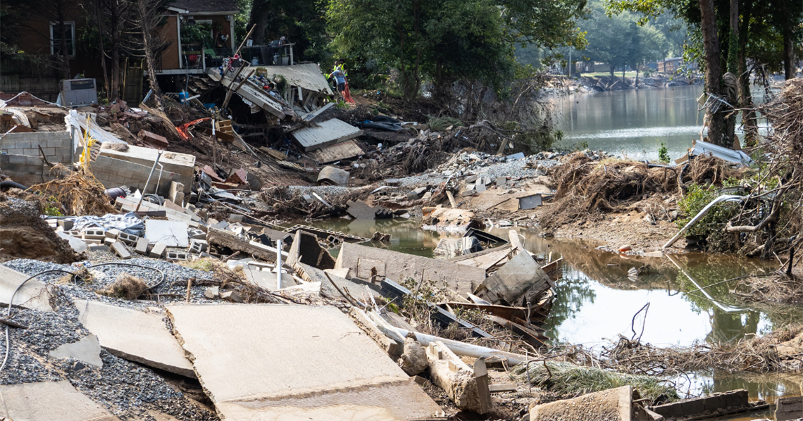 Debris from Hurricane Helene covers the foreground while volunteers and workers clean up in the background. This is in Charlotte.