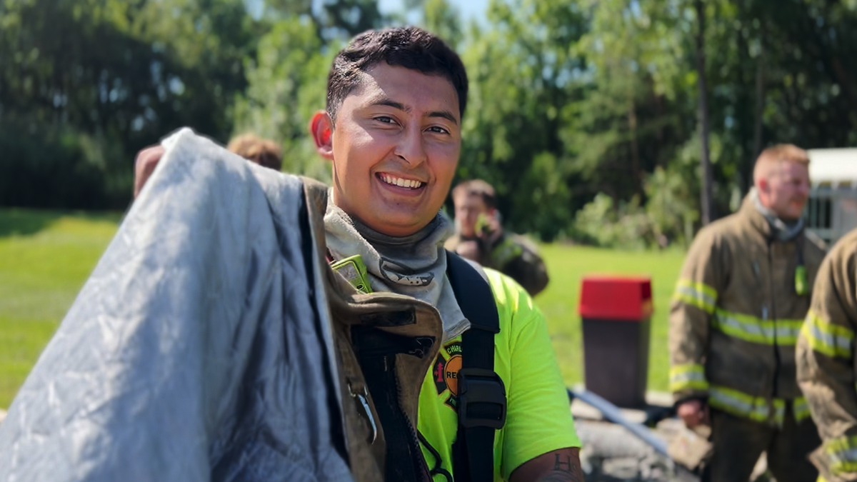 Samayoa-LaForgia smiles during training while holding out his gear for the camera.