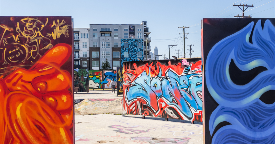 TAOH Outdoor Gallery, the Peoples' Choice Award winner. Two pieces of art frame the edges of the photo in red and blue. Between them, we see more art throughout the urban gallery.