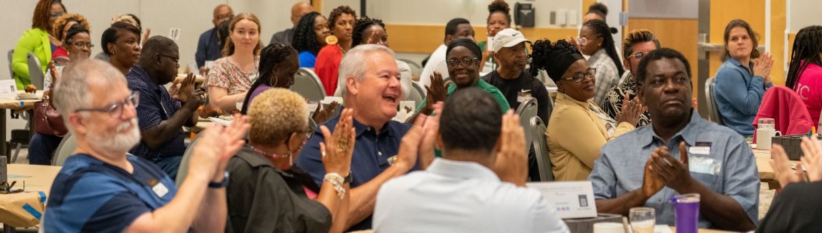 Charlotte residents at community event, smiling and clapping.