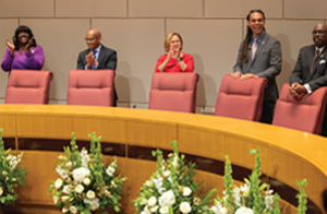 Council members standing behind chairs