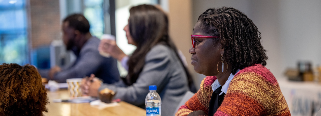 Members of a previous AMP Up cohort meet. The woman in frame listens closely during a presentation.